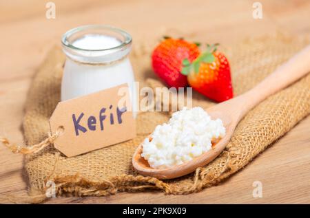 Kefir-Körner in Holzlöffel vor Tassen Kefir-Joghurt Parfaits. Kefir ist eine der besten gesunden Lebensmittel, die mit starken Probiotika zur Verfügung stehen. Stockfoto