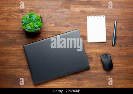 Flach liegendes Foto eines Bürotischs mit Laptop, Notebook, digitalem Tablet, Bleistift auf Holzhintergrund. Desktop-Office-Mockup-Konzept. Stockfoto