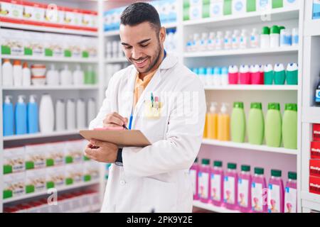 Junger hispanischer Apotheker, der auf einem Dokument in der Apotheke schreibt Stockfoto