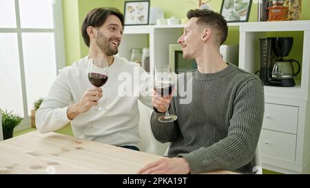 Zwei Männer, die selbstbewusst ein Glas Wein im Speisesaal trinken Stockfoto