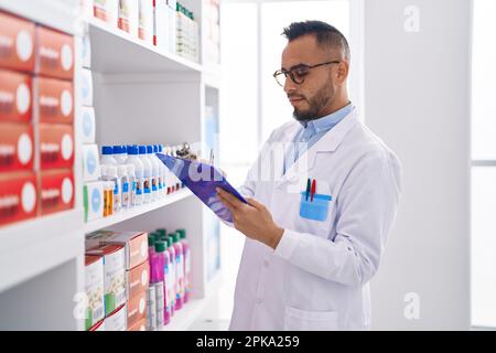 Junger hispanischer Apotheker, der auf einem Dokument in der Apotheke schreibt Stockfoto