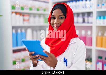Junge, schöne Apothekerin, die Touchpad benutzt und in der Apotheke arbeitet Stockfoto