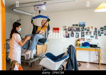 Pflegekraft bereitet die Schlafenszeit eines behinderten Patienten in seinem Zimmer im Altersheim vor. Stockfoto