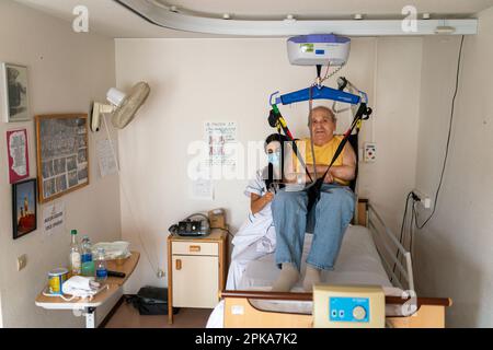 Pflegekraft bereitet die Schlafenszeit eines behinderten Patienten in seinem Zimmer im Altersheim vor. Stockfoto