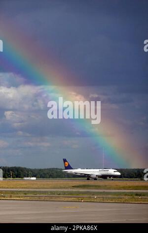 13.06.2022, Deutschland, Brandenburg, Schönefeld - Lufthansa-Flugzeug auf einer Landebahn am Flughafen BER vor einem Regenbogen. 00S220613D322CAROEX.JPG [MODELL RE Stockfoto