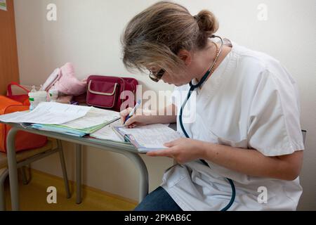 Kinderarzt, der die Krankenakte und Krankenakte des Kindes ausfüllt. Stockfoto