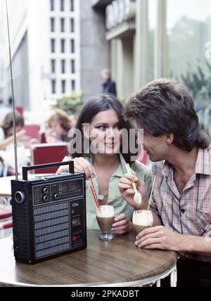 31.08.1979, Deutsche Demokratische Republik, Berlin - Junges Paar, das in einem Café Musik aus einem tragbaren Radio hört. 00S790831D015CAROEX.JPG [MODELL REL Stockfoto