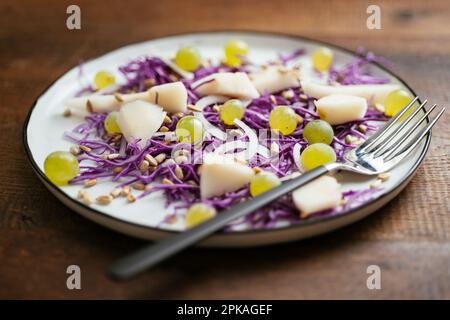 Hausgemachten gesunden Rotkohlsalat mit Birnen und Trauben auf einem Teller. Stockfoto