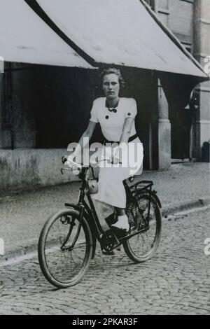 Altes Schwarz-Weiß-Foto einer jungen Frau auf einem Fahrrad Stockfoto