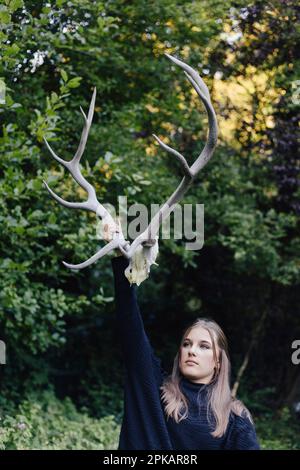 Ein Mädchen, das ein großes Geweih in der Luft hält Stockfoto