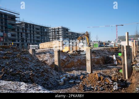 Auf einer großen Baustelle im Winter gräbt ein gelber Bagger eine Grube Stockfoto