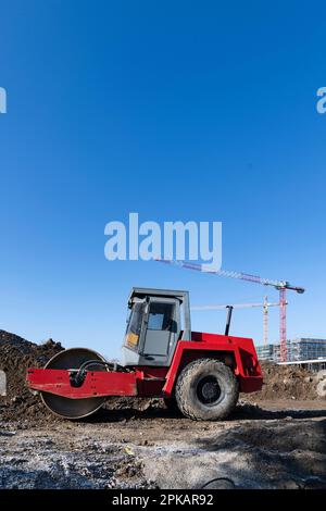 Rote Rollenständer auf einer großen Baustelle vor dem Erdhaufen mit Baukränen im Hintergrund Stockfoto