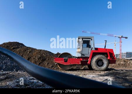 Rote Rollenständer auf einer großen Baustelle vor dem Erdhaufen mit Baukränen im Hintergrund Stockfoto