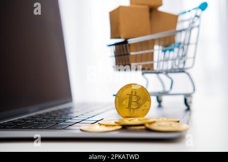 Bitcoin-Münzen und ein kleiner Spielzeugwagen mit Kartons im Hintergrund ergänzen das Mining- und Web-Banking-Konzept. Stockfoto