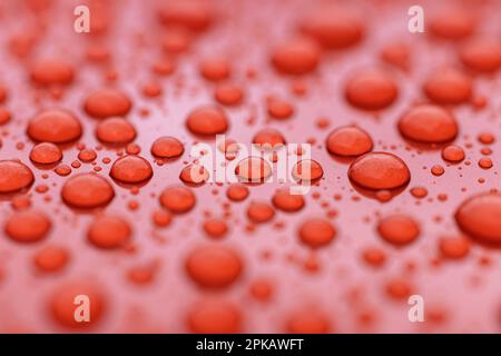 Regentropfen auf orangefarbener Autolackierung, Details, Unschärfe, Stockfoto