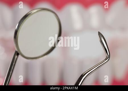 Mundspiegel, Dentalsonde, Detail, Zahnpflegemodell im Hintergrund, Symbol-Bild, Zahnpflege, Zahnvorsorge, Stockfoto