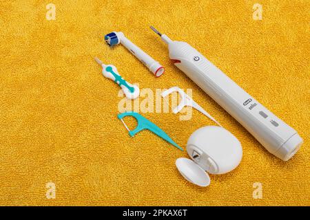Braun Oral B Typ 3766 elektrische Zahnbürste, Zahnbürste, Zahnseide, Zahnseide, Zahnzwischenbürste, Legen Sie sich auf ein gelbes Handtuch. Stockfoto