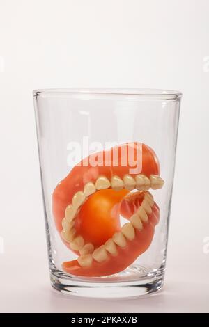 Prothese in leerem Wasserglas, Symbolbild, saubere Prothesen, weißer Hintergrund, Stockfoto