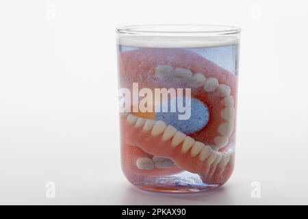 Zahnersatz mit Reinigungstablette in Wasserglas, Symbolbild, sauberer Zahnersatz, weißer Hintergrund, Stockfoto