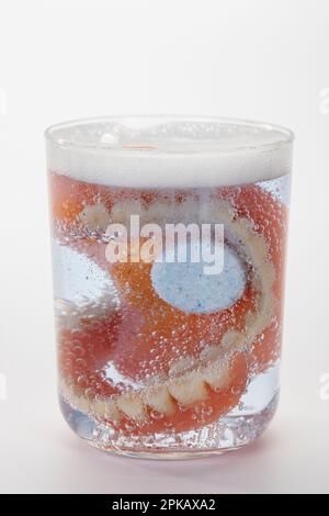 Zahnersatz mit Reinigungstablette in Wasserglas, Symbolbild, sauberer Zahnersatz, weißer Hintergrund, Stockfoto