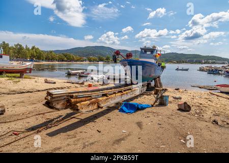 Fischerboote auf Ständen, die darauf warten, repariert und auf dem Reparaturhof für Boote lackiert zu werden, Neos Marmaras, Sithonia, Griechenland. Stockfoto