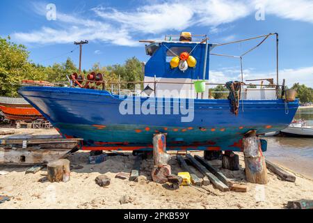 Fischerboote auf Ständen, die auf Wartung warten, die auf dem Reparaturhof für Boote repariert und lackiert werden sollen, Neos Marmaras, Sithonia, Griechenland. Stockfoto