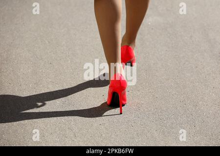 Beine einer schlanken Frau in roten Schuhen mit hohen Absätzen und Strümpfen, die die Straße entlang läuft. Weibliche Mode im Frühling Stockfoto