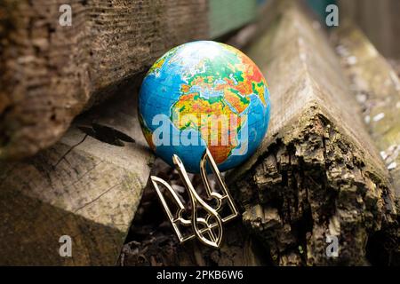 Der Globus und das Wappen der Ukraine liegen auf Holzbrettern im Hof Stockfoto