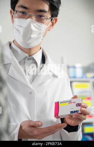 Erklärung eines Apothekers über ein Medikament (Amoxicillin) gegenüber einem Klienten. Stockfoto