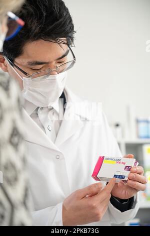 Erklärung eines Apothekers über ein Medikament (Amoxicillin) gegenüber einem Klienten. Stockfoto