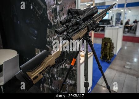 Brünn, Tschechien - 08. Oktober 2021: Modernes Gewehr auf einem großen Stativ mit Scharfschützenoptik oben auf der Waffen- und Verteidigungsmesse Stockfoto