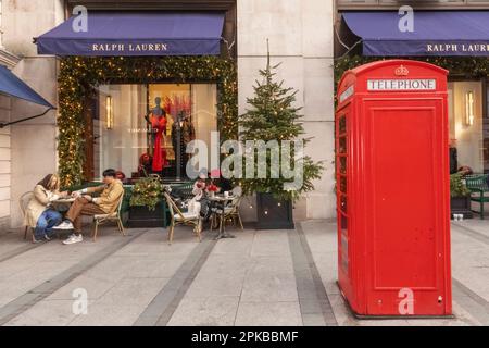 England, London, Piccadilly, New Bond Street, Außenansicht des Ralph Lauren Store mit Weihnachtsdekorationen und traditioneller roter Telefonzelle Stockfoto