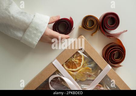 Das Kind nimmt kandierte Früchte aus einem Set mit verschiedenen Früchten - kandierte Früchte. Nachtisch als Geschenk. Stockfoto