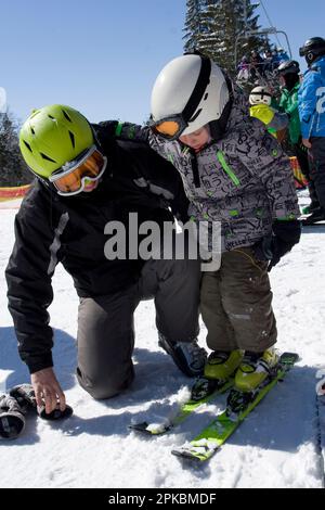 Dad Skifahrer hilft Sohnes, Skier in den Alpen zu platzieren Stockfoto