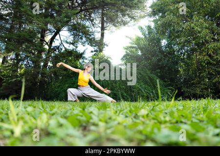 Eine Frau, die draußen Tai Chi Chuan praktiziert. Das Üben von Tai Chi kann dazu beitragen, die Flexibilität, Kraft und das Gleichgewicht des Körpers zu verbessern und Stress zu reduzieren Stockfoto