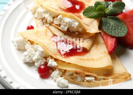 Leckere dünne Pfannkuchen mit Hüttenkäse und Marmelade auf dem Teller, Nahaufnahme Stockfoto
