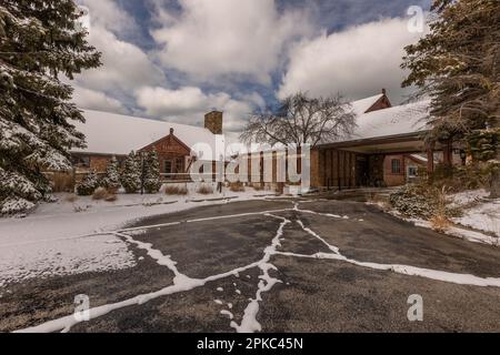 Verlassene alte Bar (Backsteingebäude) in Michigan mit Schnee bedeckt. Ein großer Hof davor. Winterzeit. Stockfoto