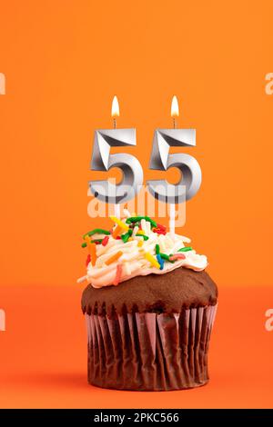 Kerze Nummer 55 - Kuchen zum Geburtstag auf orangefarbenem Hintergrund Stockfoto