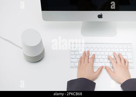 AI-Lautsprecher neben einem Computer auf einem weißen Schreibtisch Stockfoto