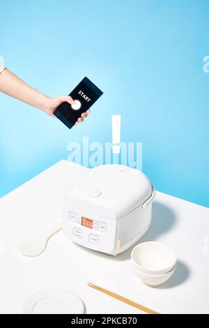 Smartphone, das einen Reiskocher bedient Stockfoto