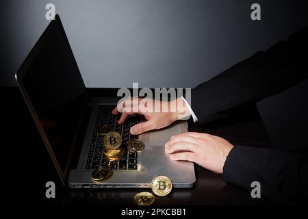 Ein Mann im Anzug, der Bitcoin-Geschäfte mit dem Computer macht Stockfoto