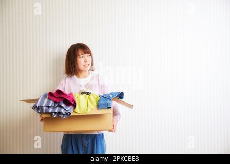 Frau trägt Kleidung in Pappkartons Stockfoto