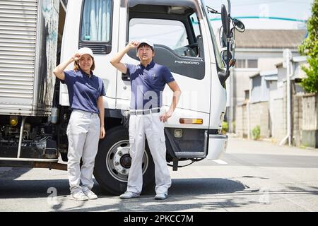 Arbeitende Männer und Frauen, die vor einem großen Truck posieren Stockfoto