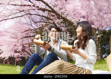 Ein Paar isst Bento unter dem Kirschbaum Stockfoto