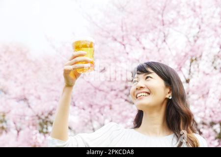 Eine Frau, die Bier unter dem Kirschbaum trinkt Stockfoto