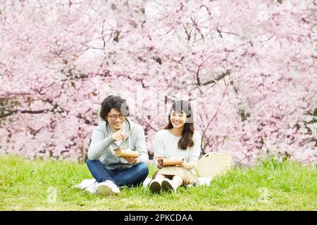 Ein Paar isst unter dem Kirschbaum zu Mittag Stockfoto