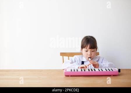 Ein Mädchen, das am Tisch Mundharmonika spielt Stockfoto