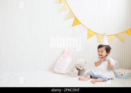 Baby mit Partyhut, umgeben von Geschenken Stockfoto