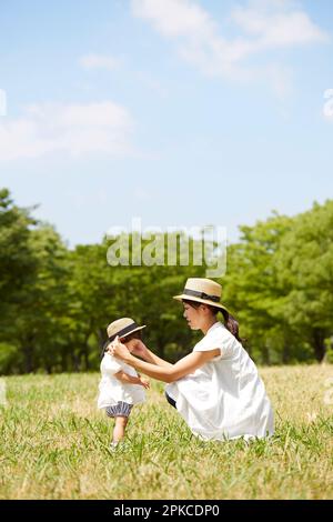 Mutter und Tochter tragen passende Hüte auf dem Gras Stockfoto