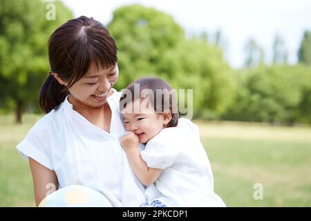 Das Baby wird von der Mutter im Park getragen Stockfoto